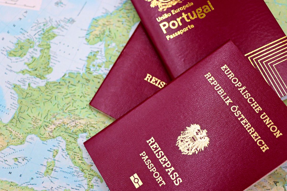 Close-up of European passports from Portugal and Austria on a world map.