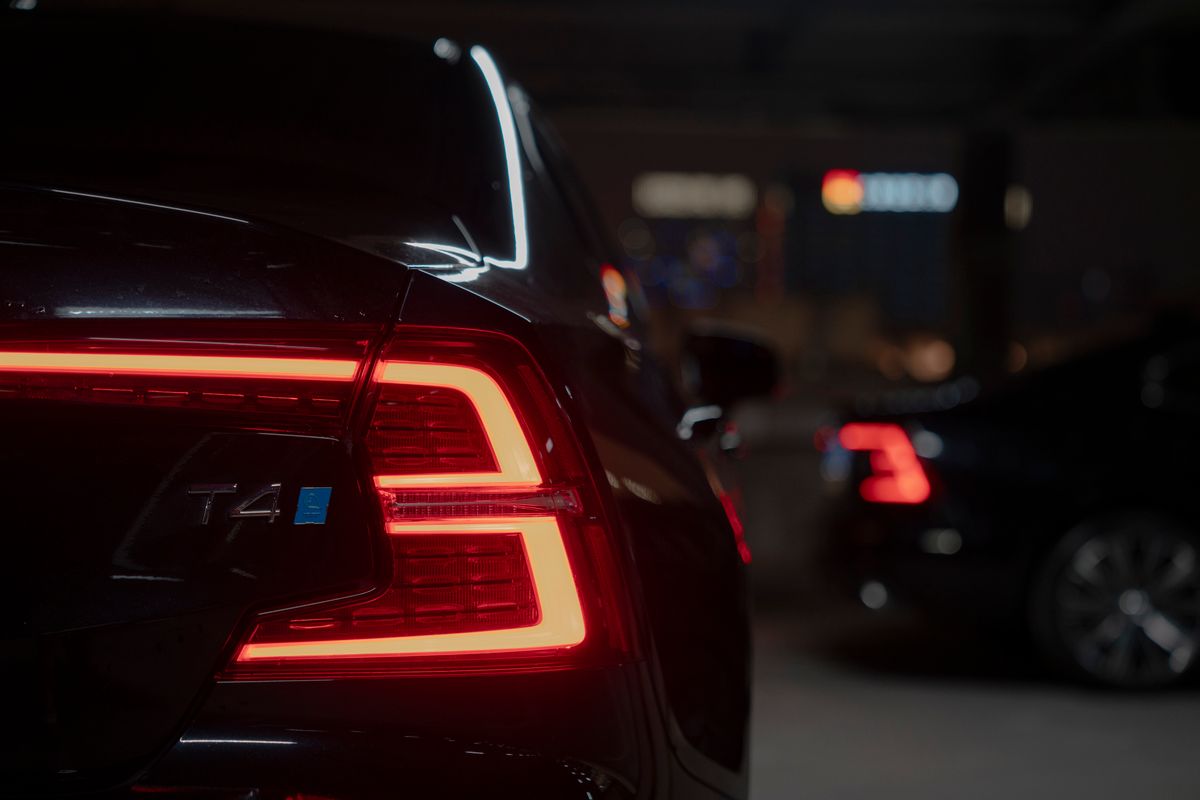 Dark moody image of a car tail light glowing vividly in a dimly lit parking area at night.