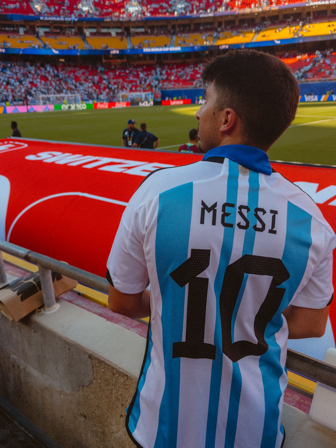 Trump Defends FIFA’s Gianni Infantino as Soccer’s Biggest Power Struggle Raises Questions About Money, Politics, and the Future of the Game 4 Fan in Argentina jersey with 'Messi 10' watching football match at crowded stadium.
