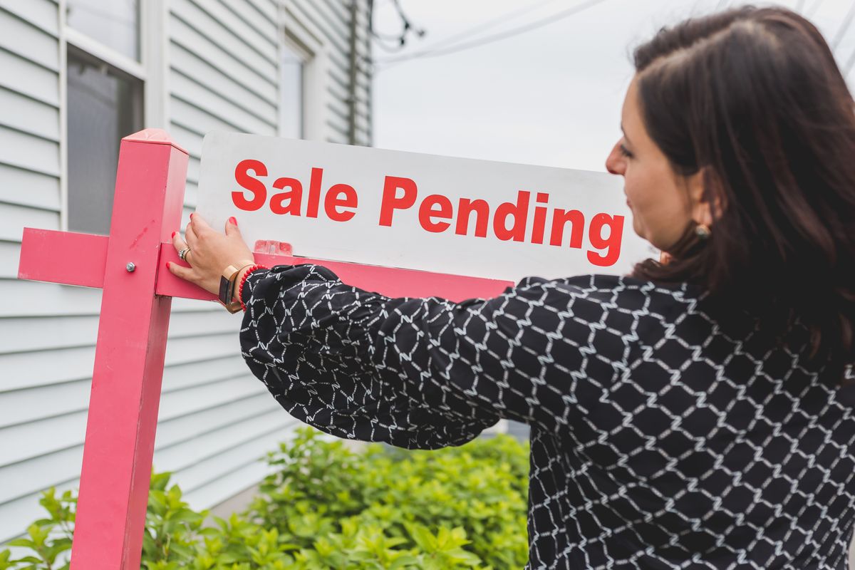 The 2026 Housing Market Just Shifted, and Buyers Finally Have Some Breathing Room 2 Female realtor adjusts sale pending sign on a property, indicating an upcoming sale closure.