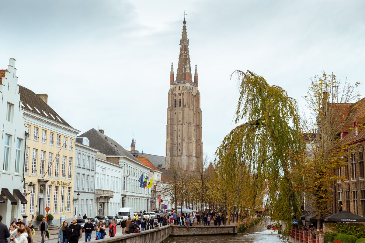 Gothic church tower view in Bruges with canal and street views, showcasing classic architecture.