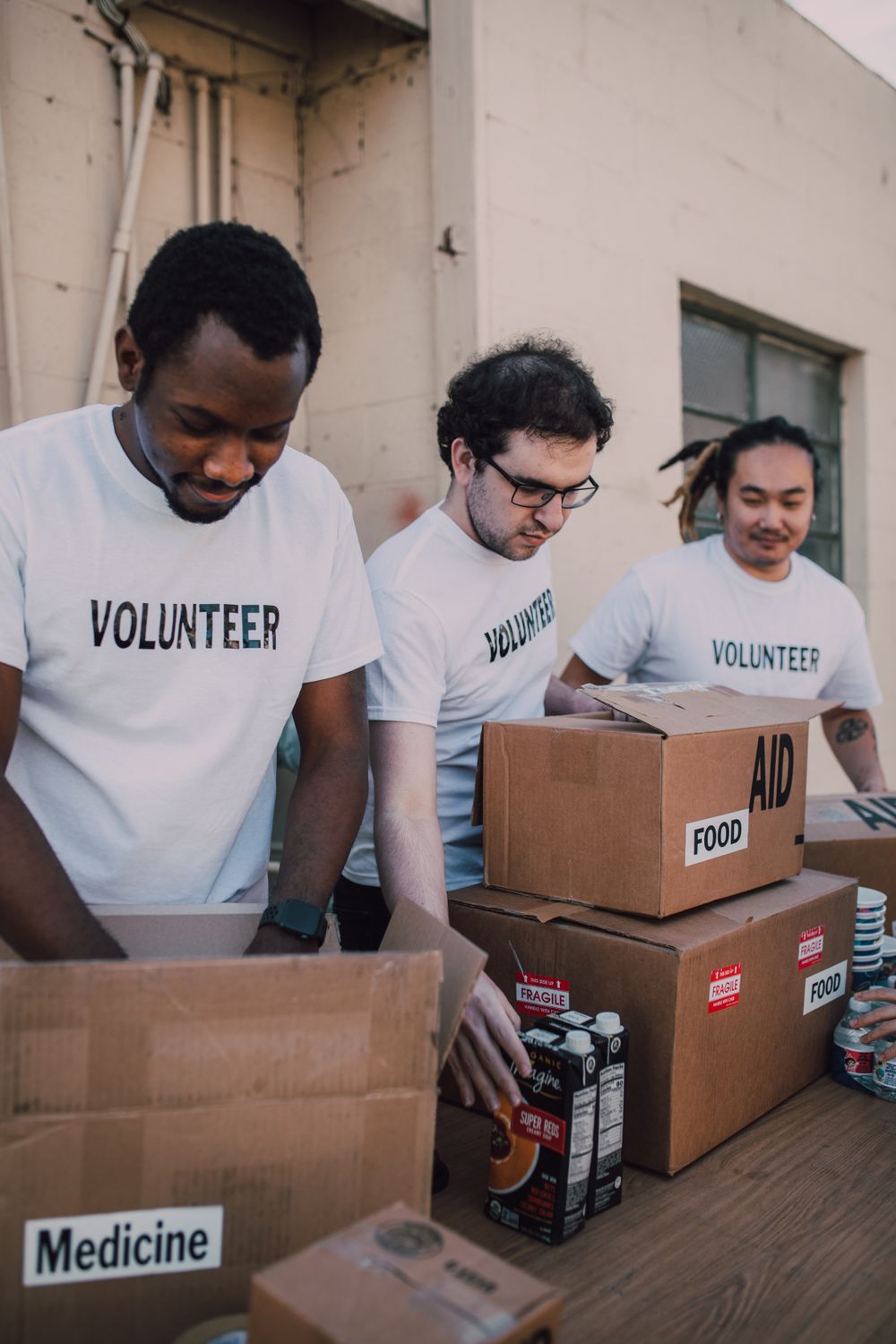 Community Impact 101: How Businesses Are Quietly Reshaping Local Communities (and Why It Matters More Than Ever) 1 Group of volunteers preparing food and medicine boxes for charity distribution.