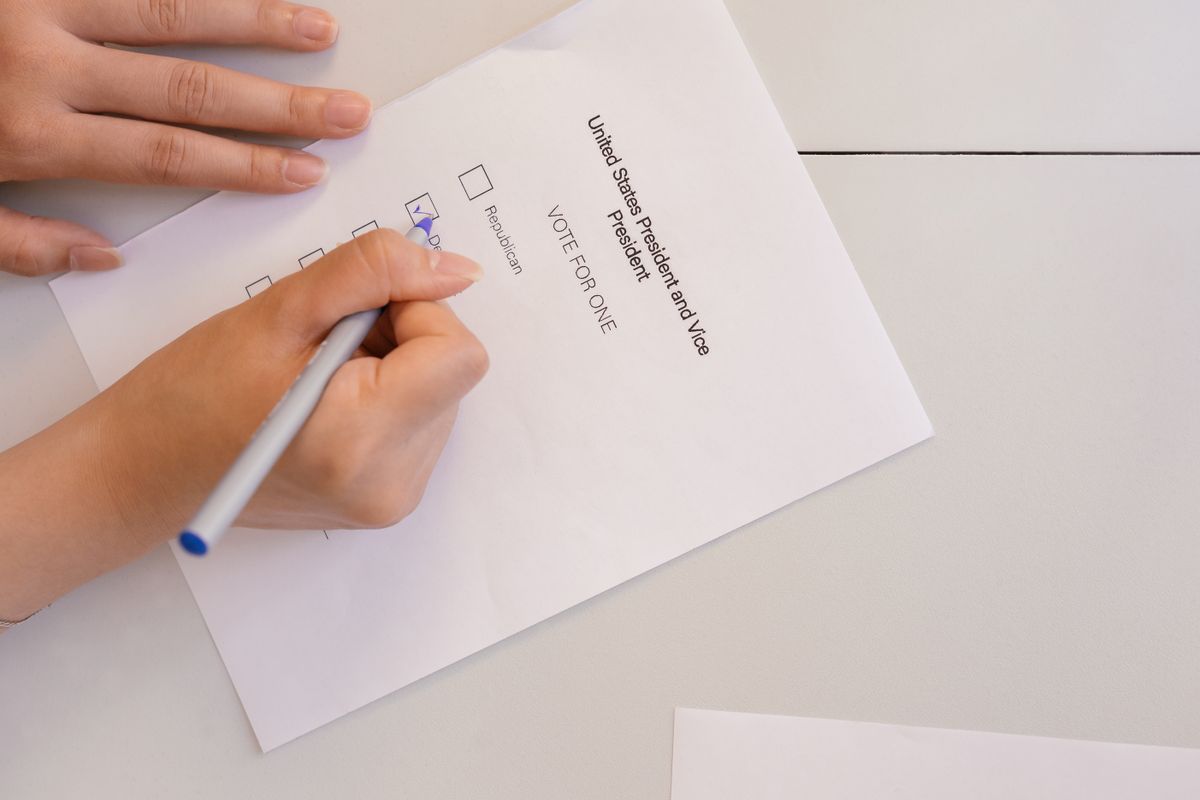 Hand-placing a vote on a ballot form during election process, highlighting civic duty and democracy.