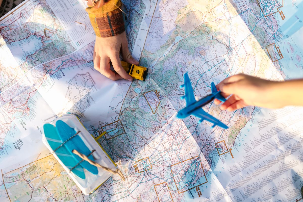 U.S. Issues Worldwide Travel Caution as 23 Countries Remain at ‘Do Not Travel’ Level 2 Hands holding a toy airplane and car over a map, symbolizing travel planning and exploration.