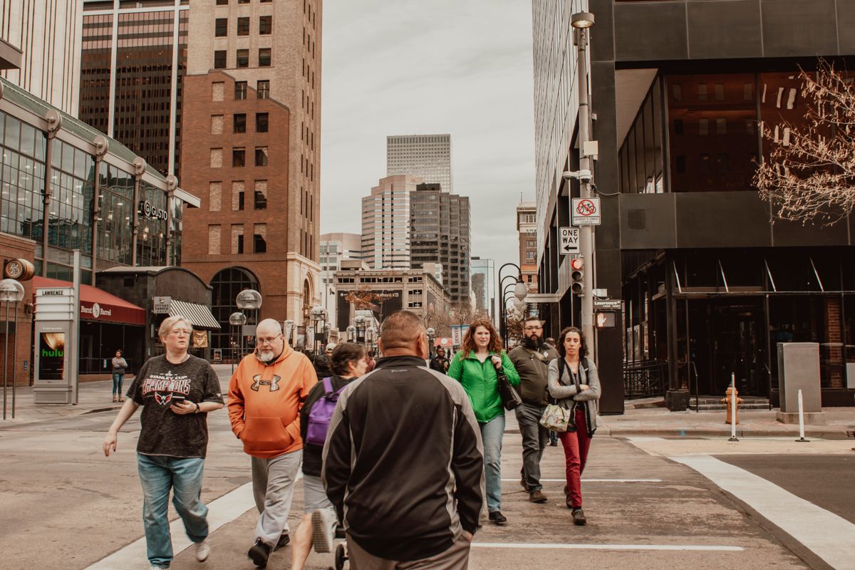 New Data Reveals the States in the U.S. With the Lowest Cost of Living in 2026 1 Lively urban street with diverse people crossing amidst modern city buildings.