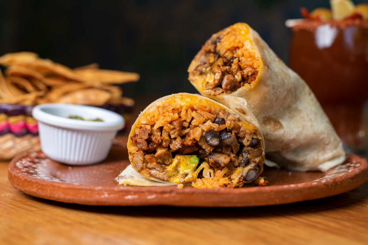 Chipotle Takes Its Biggest Gamble Yet as It Brings American Burritos Into Mexico’s Taco Kingdom 4 Mouthwatering beef and rice burrito served on a rustic plate with chips.