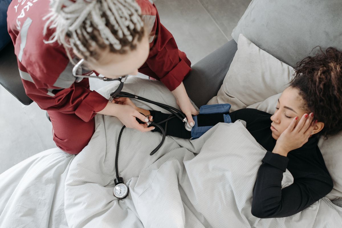 America’s immigration crackdown could push its caregiver crisis over the edge. 2 Paramedic measuring patient's blood pressure indoors, illustrating home healthcare assistance.