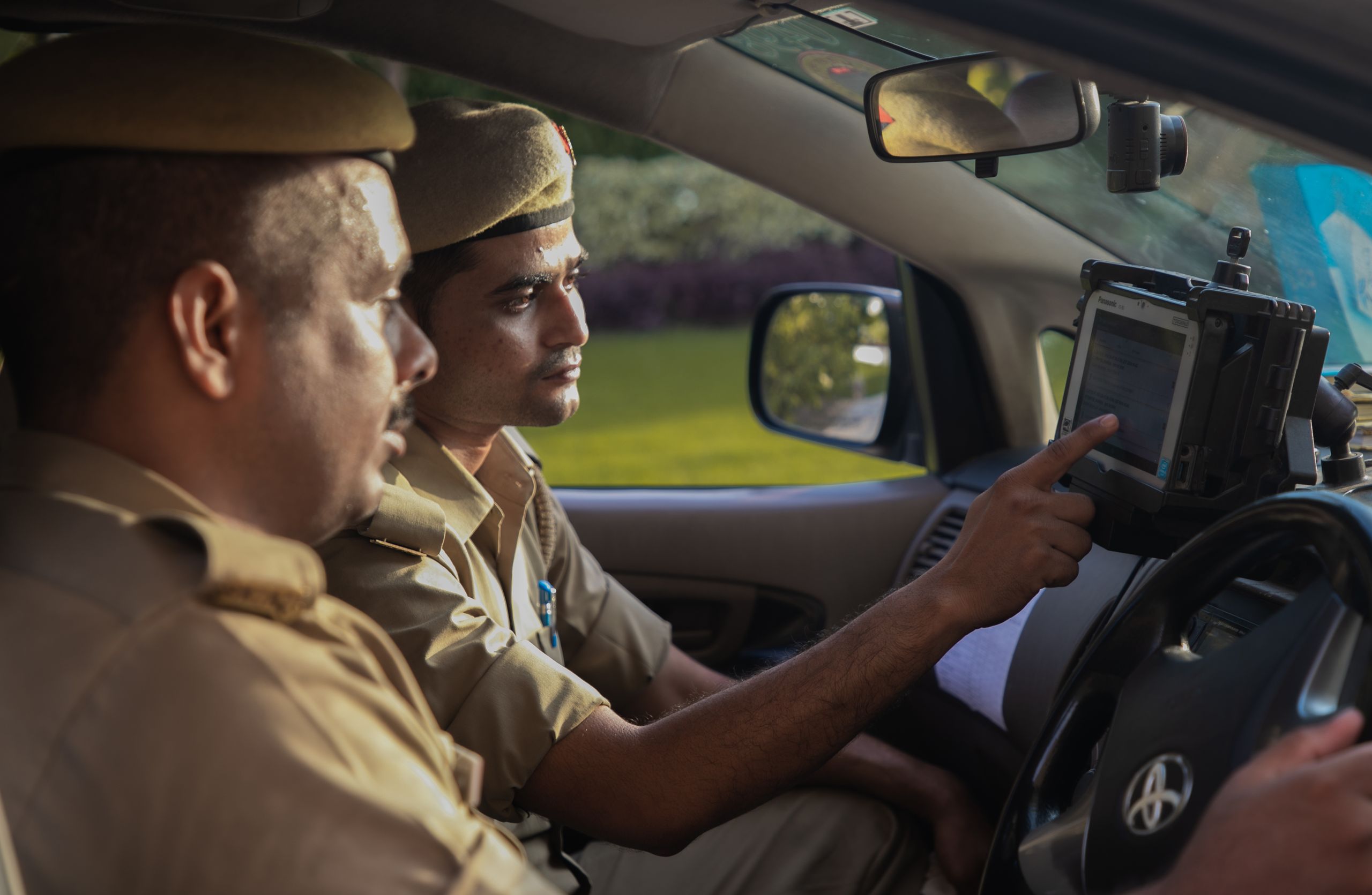 Police officers using a tablet inside a patrol car, enhancing efficiency.