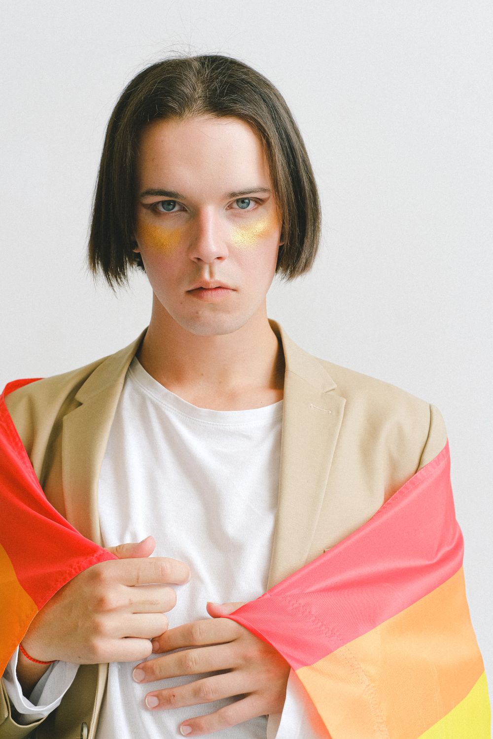 Portrait of a young adult with rainbow flag symbolizing LGBTQ pride.