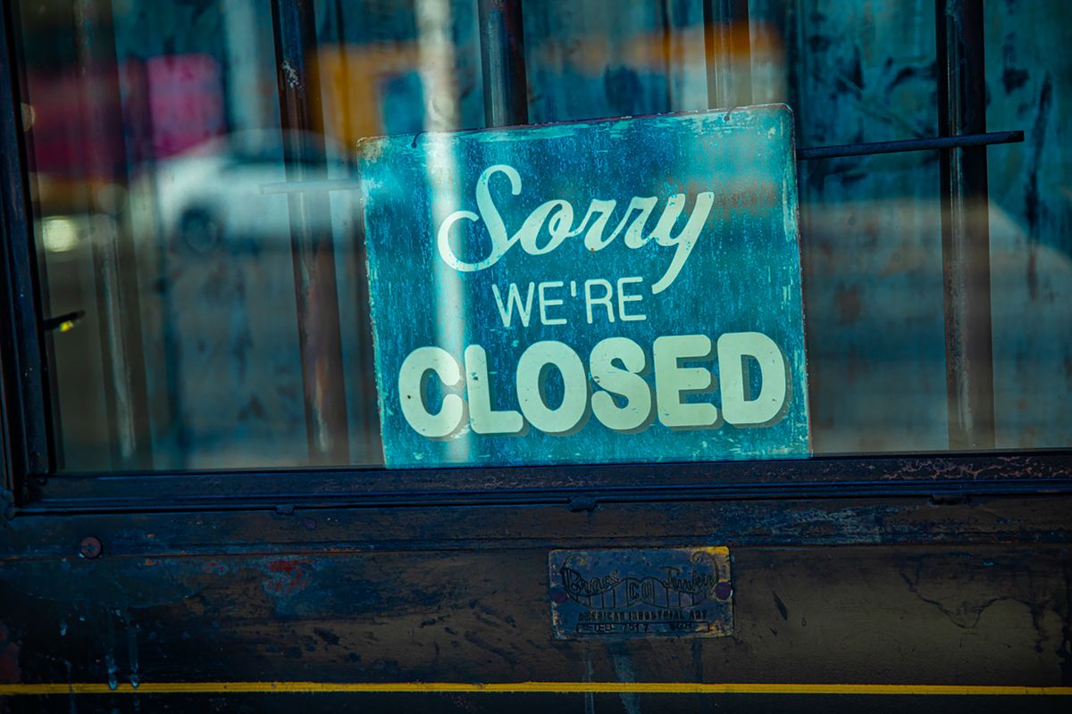 Retro 'Sorry We're Closed' sign displayed on a rustic glass door, depicting temporary closure.