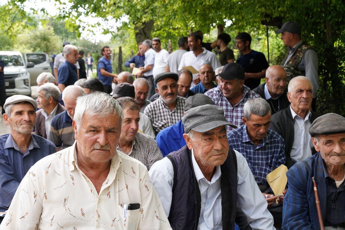 A Medicare Part D Squeeze Is Coming in 2027 as Premium Support Disappears 2 Senior men gathered outdoors, engaging in social interaction under trees.