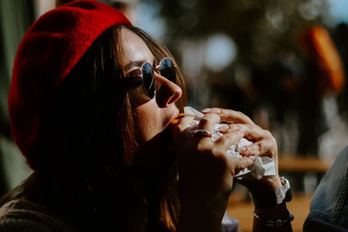 Chipotle Takes Its Biggest Gamble Yet as It Brings American Burritos Into Mexico’s Taco Kingdom 1 Stylish woman in sunglasses eating outdoors, savoring her meal in the sun.