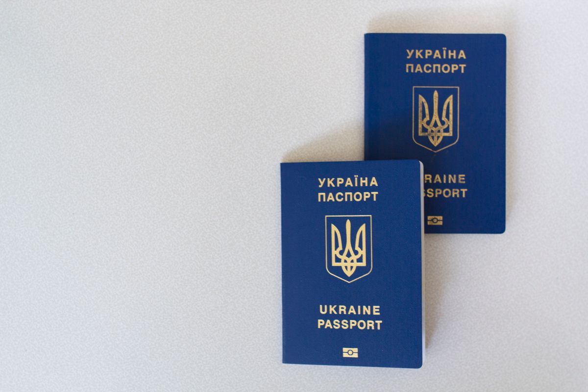 Trump’s Patriot Passport turns America’s travel document into a personal billboard. 2 Two blue Ukrainian passports placed on a white surface, close-up view.