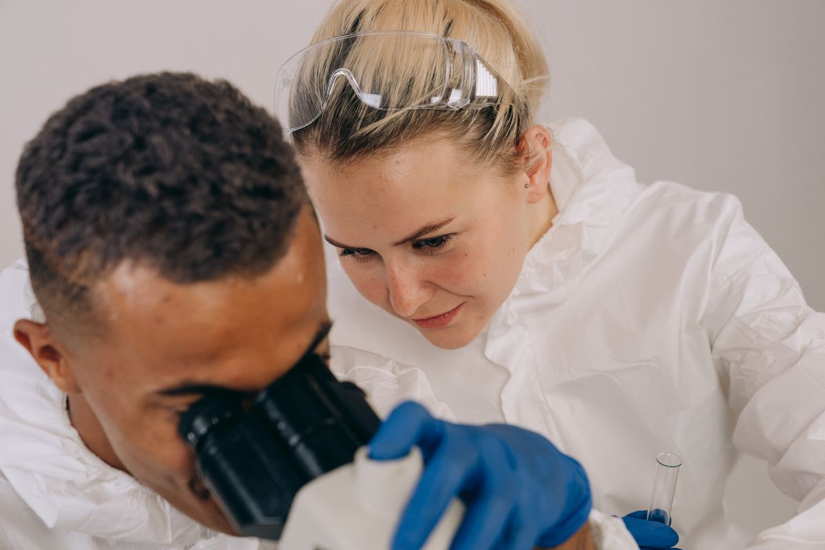 FDA Says Taylor Farms Lettuce Test Was A False Positive But Outbreak Investigation Still Points To The Supply Chain 1 Two scientists in lab gear engage in microscopic research, emphasizing collaboration and precision.