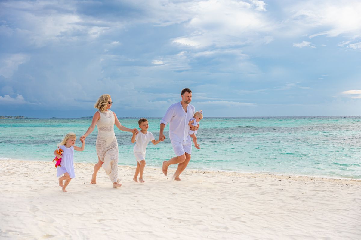 A joyful family strolls along a tropical beach, enjoying a sunny day together.