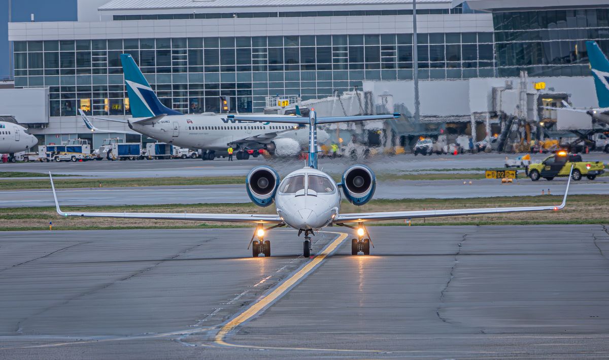 Delta Flight Passengers Evacuated by Emergency Slides After Plane Makes Unexpected Landing in Atlanta 1 A private jet on the runway at a bustling airport with commercial planes and terminal in view.