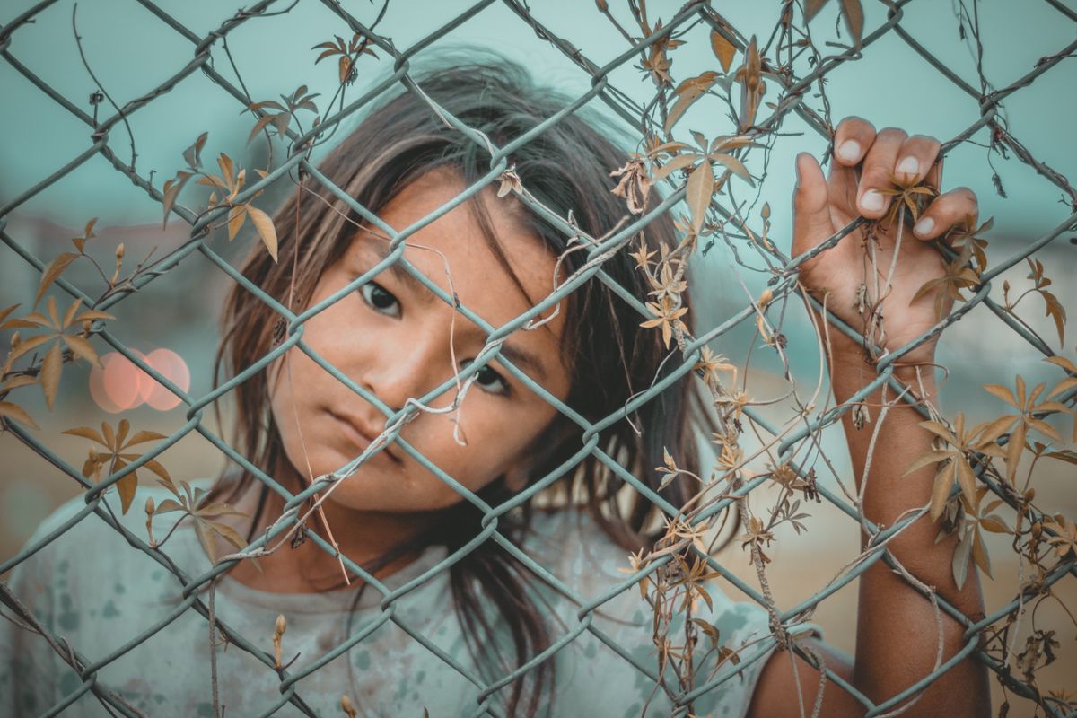 FBI Builds Unprecedented Crime-Fighting Ties With China and Russia Under Kash Patel 2 A thoughtful child gazes through a wire fence, symbolizing innocence and curiosity.