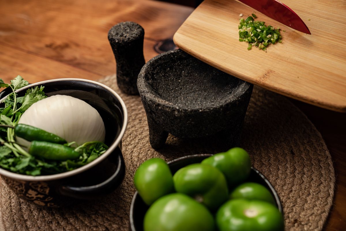 Jalapeño-Linked Salmonella Outbreak Sickens 345 People Across 27 States 1 Close-up of fresh Mexican ingredients like tomatillos, onion, and cilantro on a rustic kitchen table.