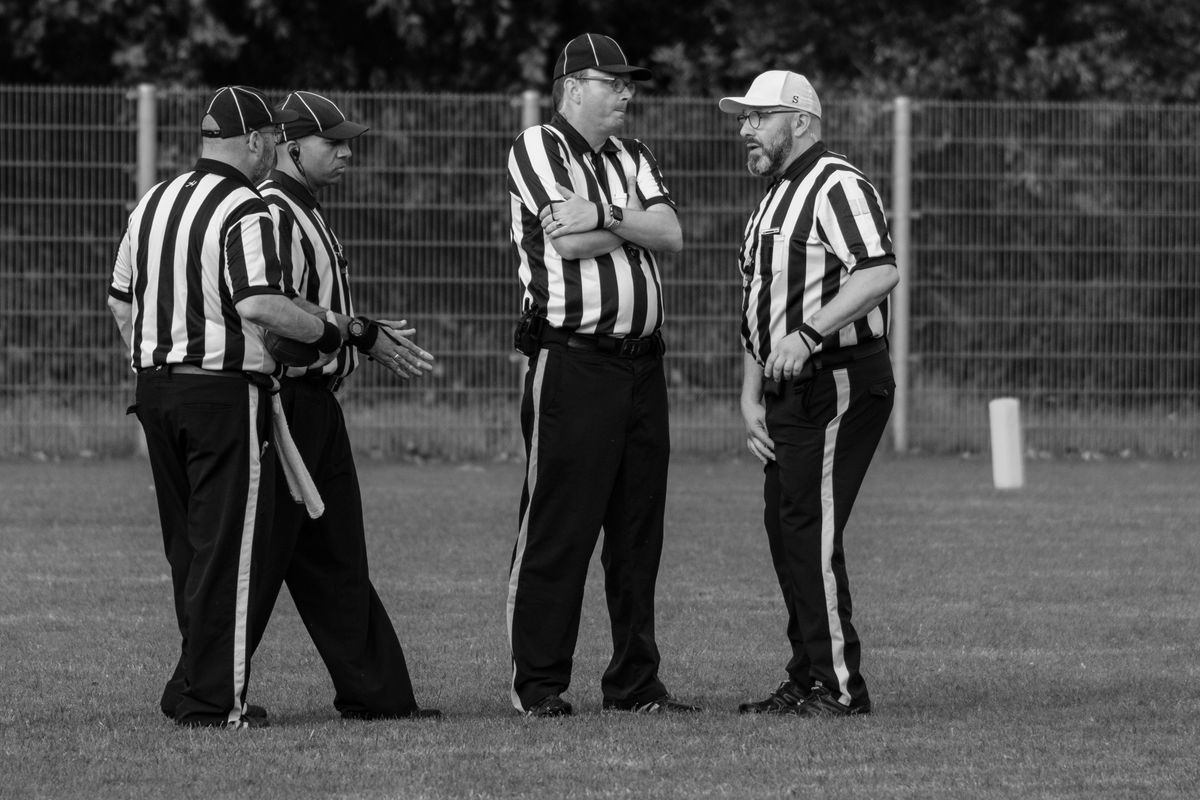 700 Drones Seized Near World Cup Events, but White House Says None Were Weaponized 1 Four referees in striped uniforms discuss on a grassy field.