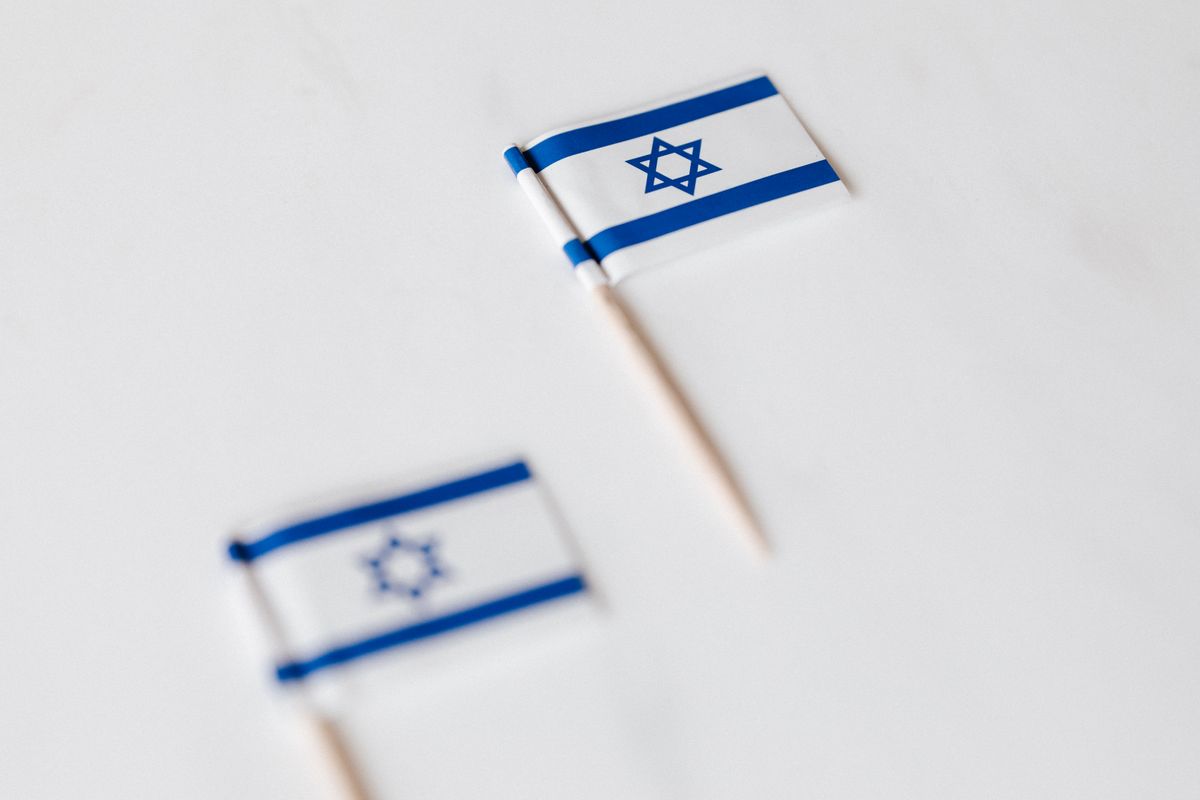 From above of small flags of Israel on toothpicks placed on white surface