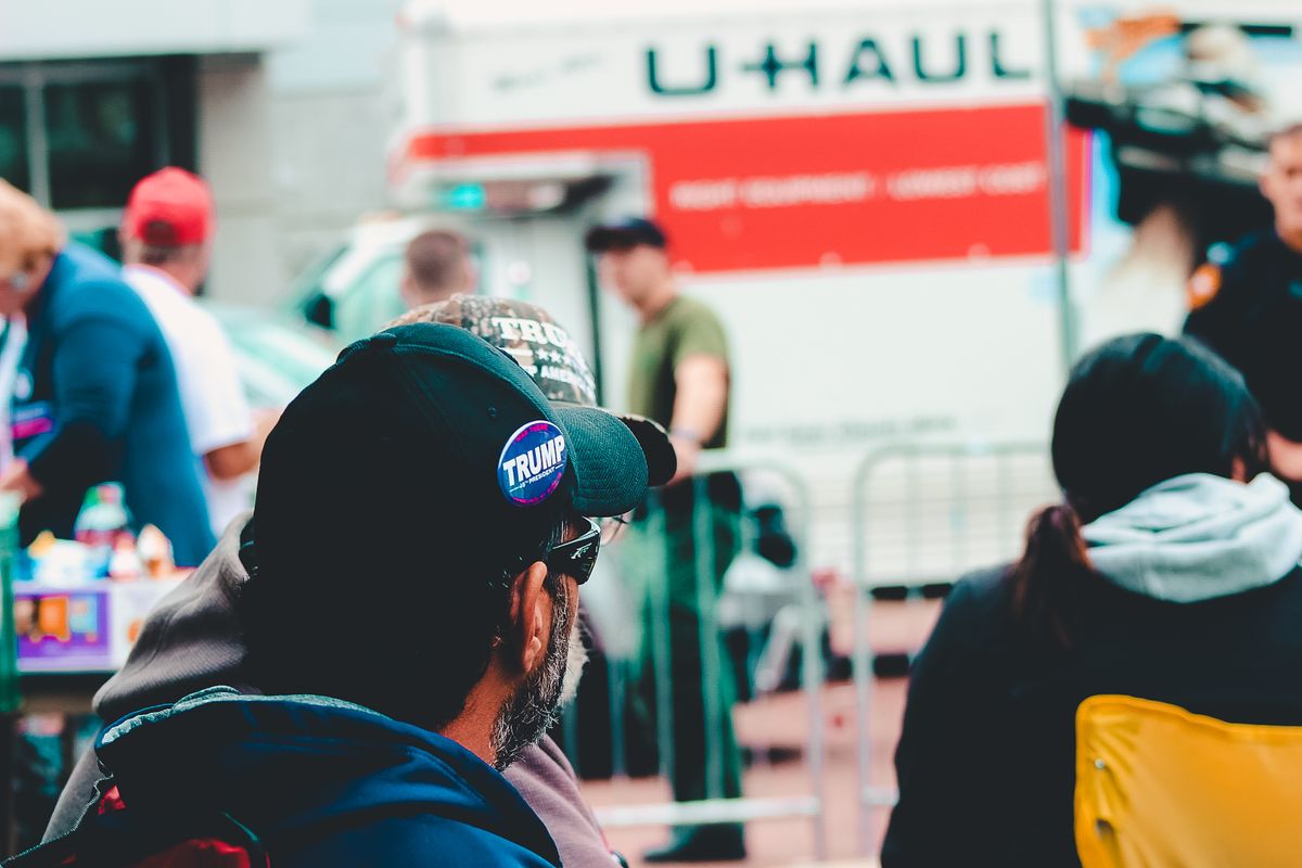 New Jersey Voter-Roll Failure Put 6,600 Noncitizens on the Rolls as Congress Demands Answers 2 Participants at a political rally in Wheeling, WV wearing campaign merchandise with a U-Haul in the background.