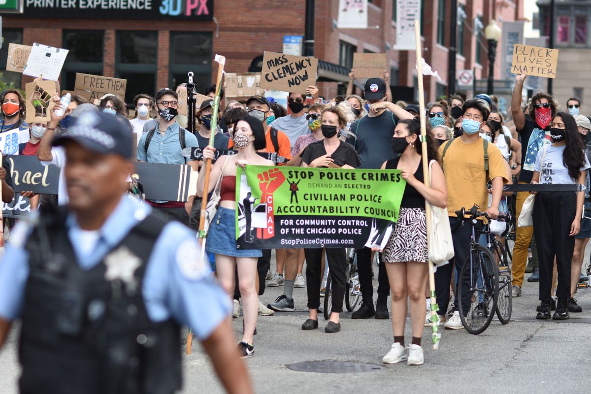 Federal Judge Blocks New York ICE Mask Ban as Fears Grow Over Hidden Identities 1 Protesters march in Chicago demanding police accountability. Diverse crowd carries signs for justice.