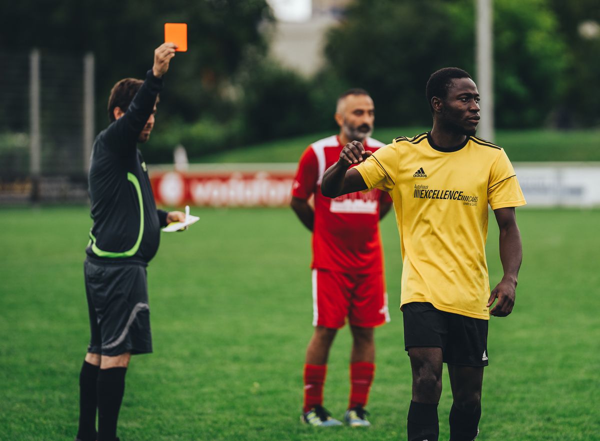 700 Drones Seized Near World Cup Events, but White House Says None Were Weaponized 3 Referee issuing a red card to a soccer player in an outdoor match setting.
