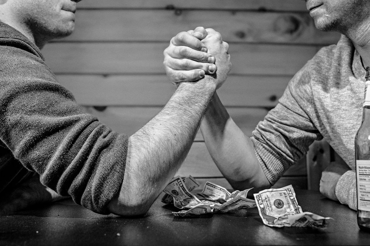 FBI Builds Unprecedented Crime-Fighting Ties With China and Russia Under Kash Patel 3 Two men engage in a high-stakes arm wrestling match surrounded by money on a table.