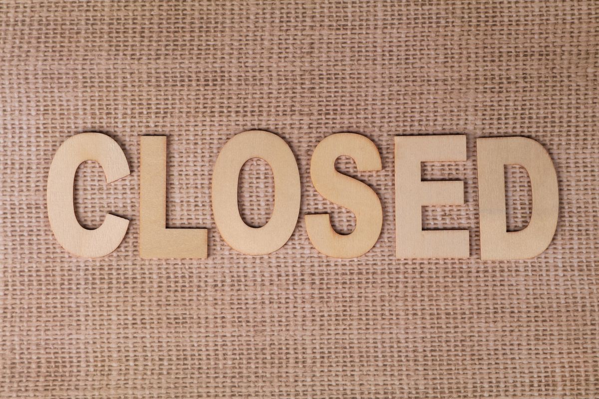 Wooden "Closed" sign on burlap fabric, ideal for business closure themes.