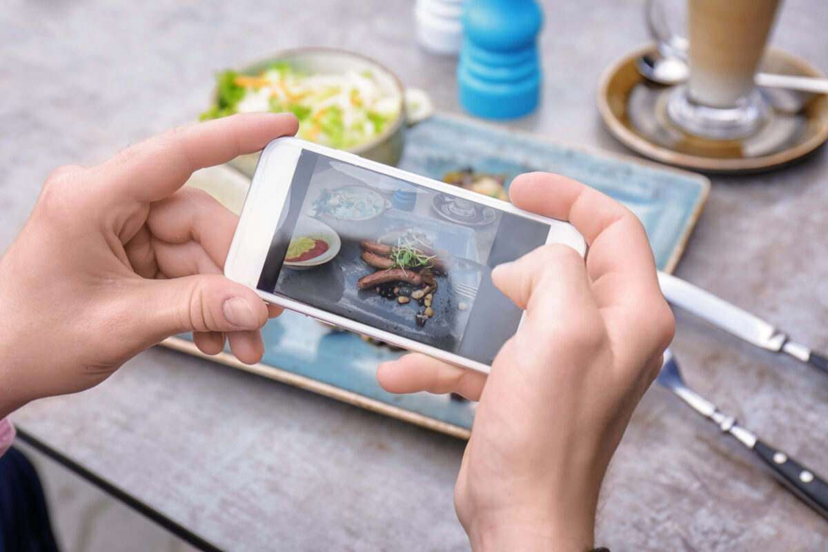 Man photographing tasty food with mobile phone, closeup