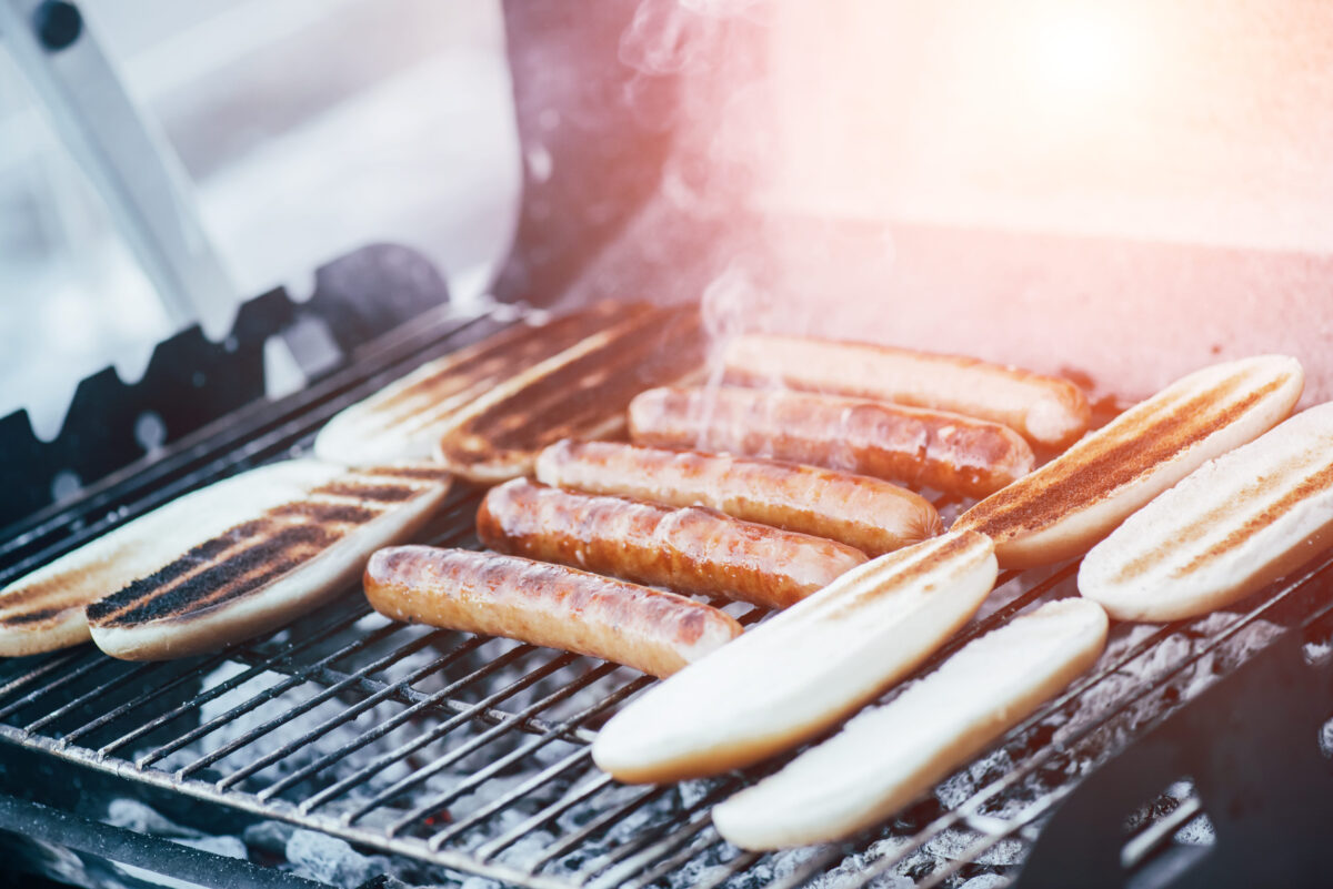 delicious hot dogs grilling with smoke on barbecue grill grade