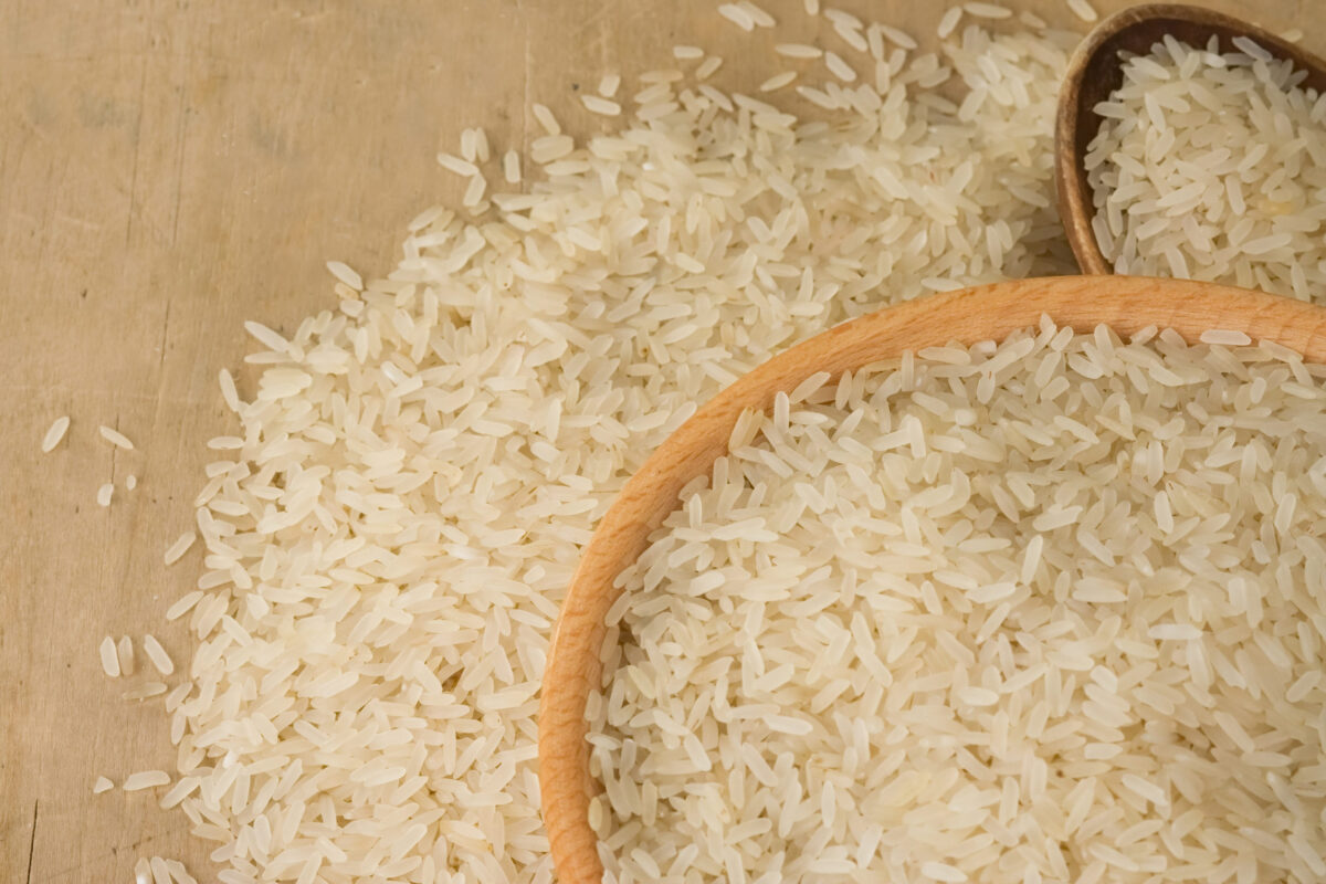 uncooked rice and wood spoon as background