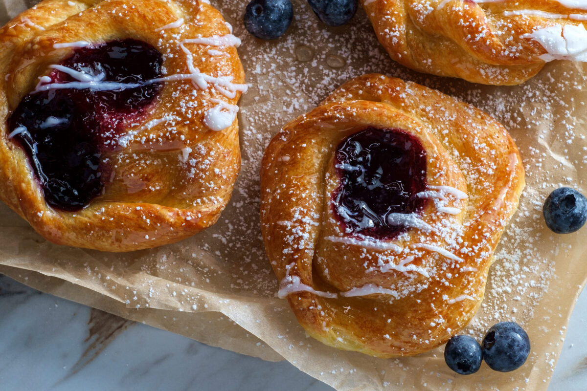 10 Popular Dishes That Aren’t From the Places They’re Named After 2 Blueberry glazed danish dessert pastries with icing and powdered sugar
