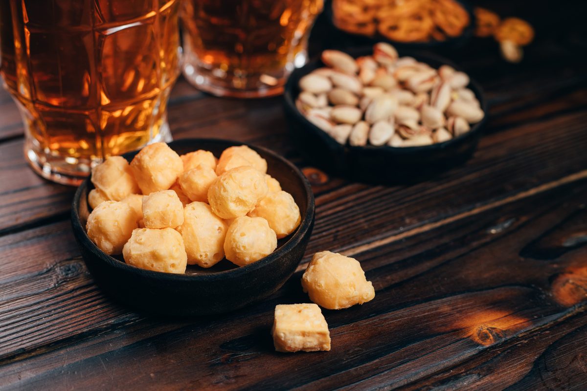Cheese balls, pretzels, nuts and two mugs of lager