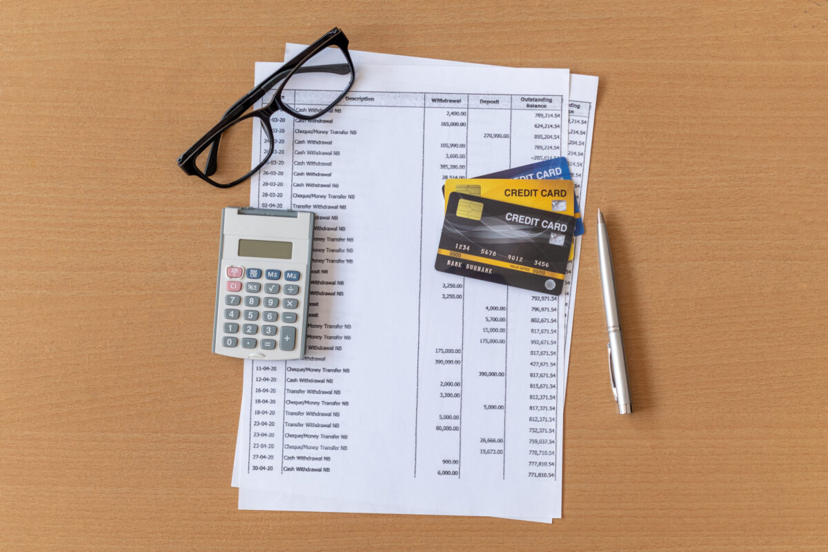 Calculator and Pen on Bank statement and credit card on a Wooden table
