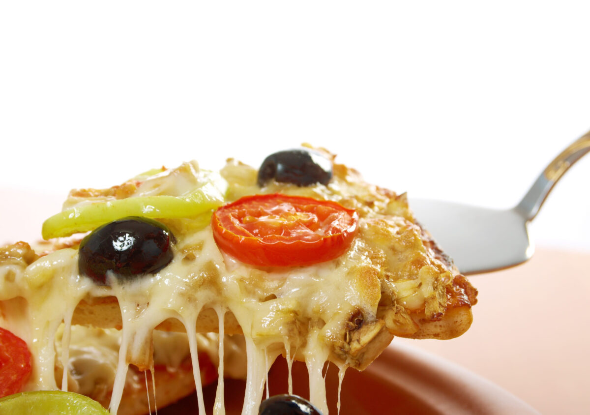7 Easy Ways to Make Frozen Pizza Taste Surprisingly Amazing 3 .home pizza with tomato and eggplant Closeup .taking slice of pizza,melted cheese dripping. isolated on white background.