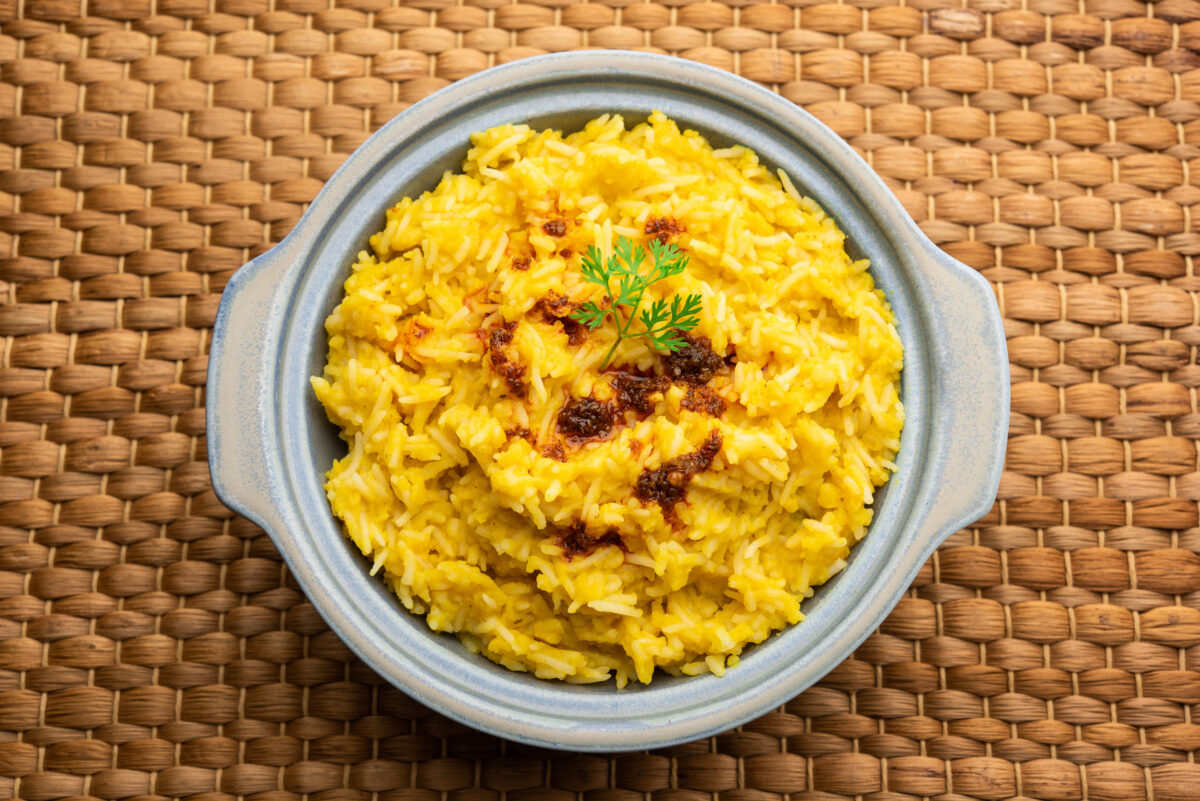 Dal khichadi or Khichdi Tasty Indian recipe served in bowl over moody background is made of toovar dal and rice combined with whole spices, onions, garlic and tomatoes