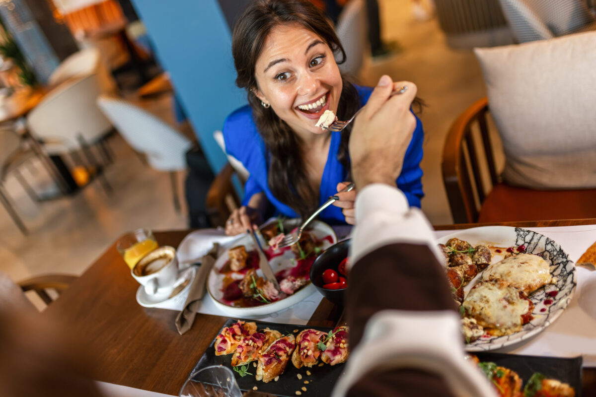 Couple feeding eachother in a restaurant with delicious food.