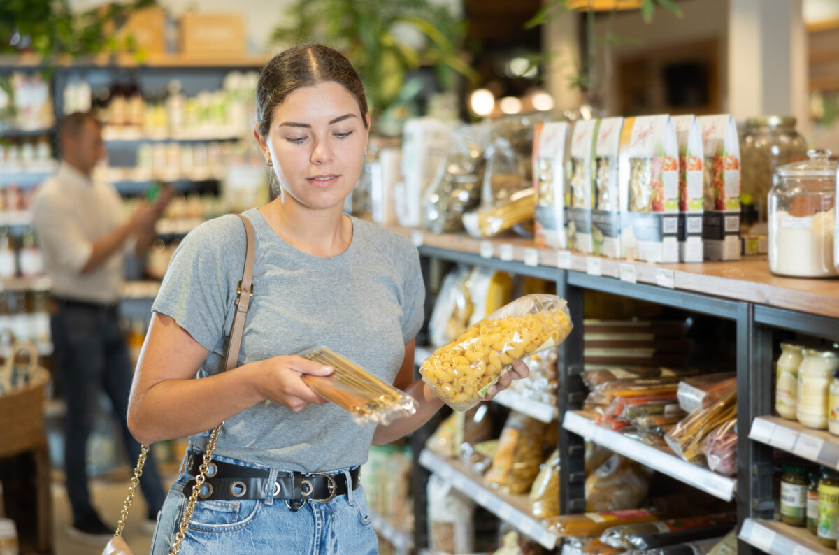 Young girl purchaser buying pasta in grocery store