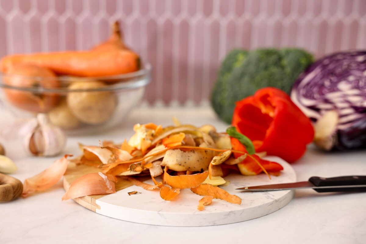 Pile of organic waste, vegetables and knife on light table, closeup