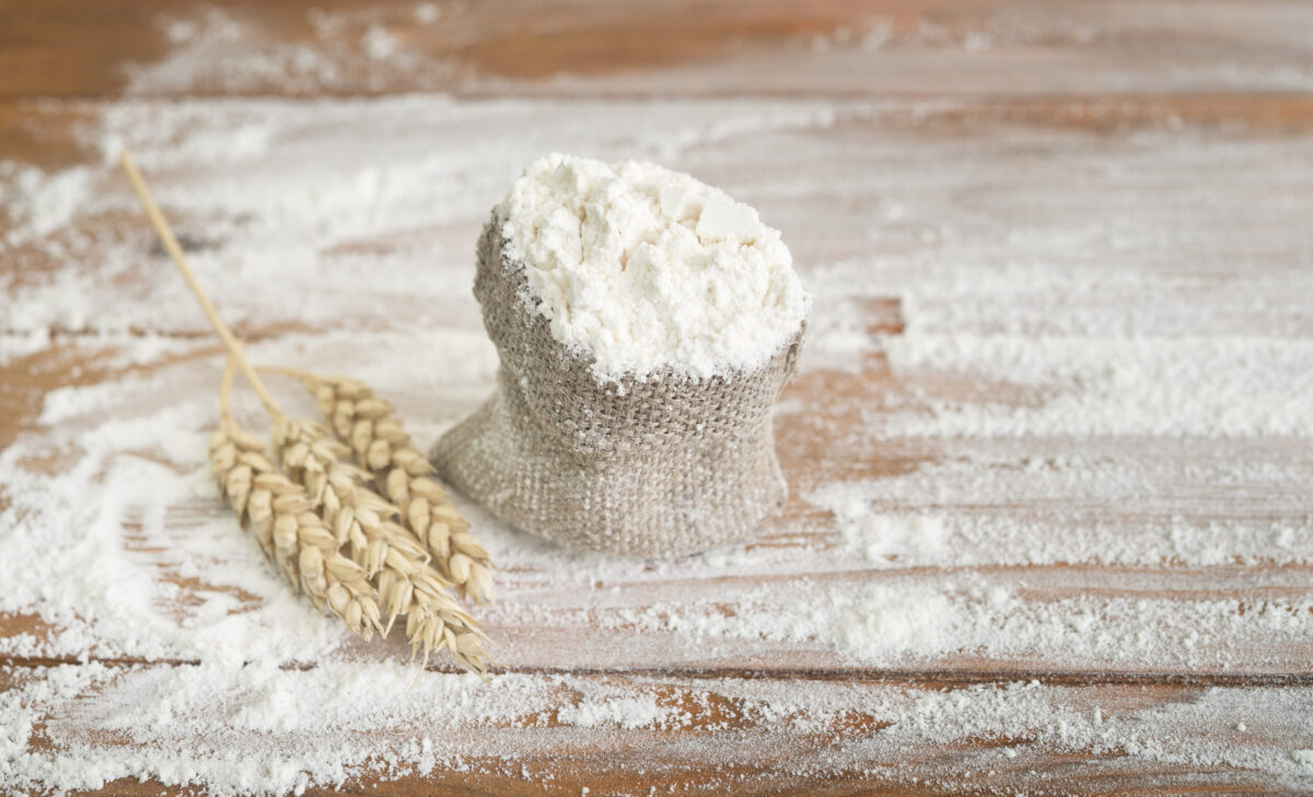 wheat flour in sack with ears on wooden table
