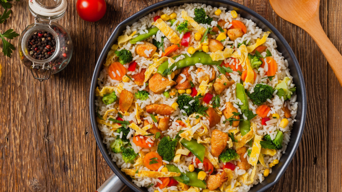 Your Bowl of Rice Doesn't Have to Be Boring: 7 Easy Ways to Make Dinner Interesting 1 A vibrant stir-fried rice dish featuring colorful vegetables and tender chicken, eggs, garnished with fresh herbs, evoking a sense of home-cooked comfort. The medley of ingredients promises a burst of flavors in every bite, perfect for a family dinner or a meal shared with friends.