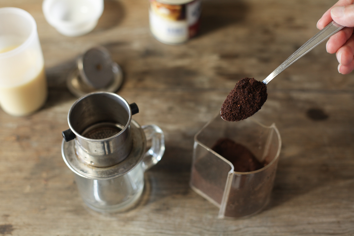 Scooping coffee into metal filter for Vietnamese coffee