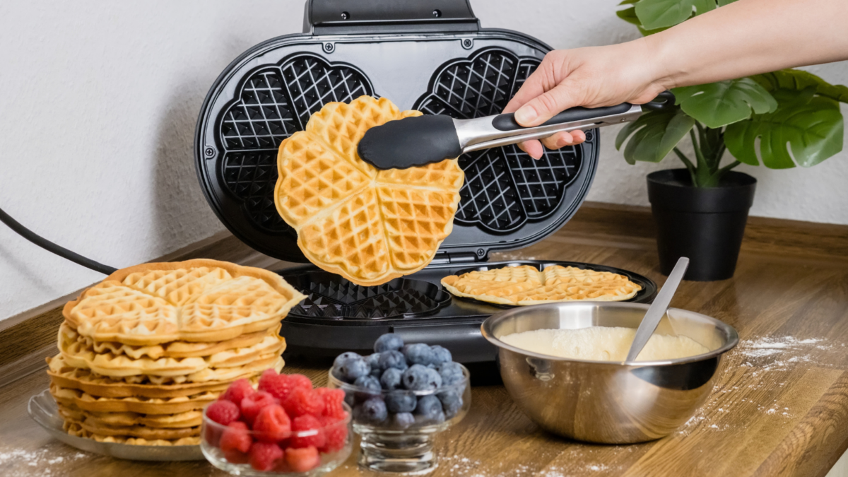 The Breakfast Debate That Never Gets Old: Waffles or Pancakes? 2 Making Belgian waffles. Female hand pours dough into waffle maker in kitchen at home.