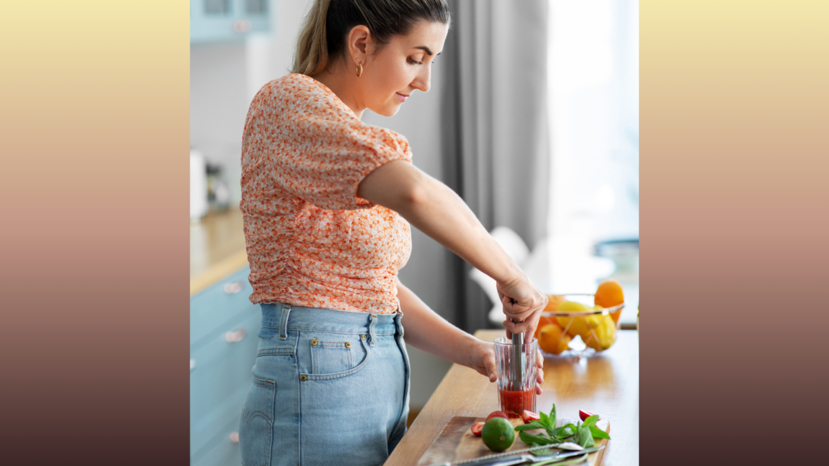  happy smiling young woman making strawberry mojito mocktail at home kitchen