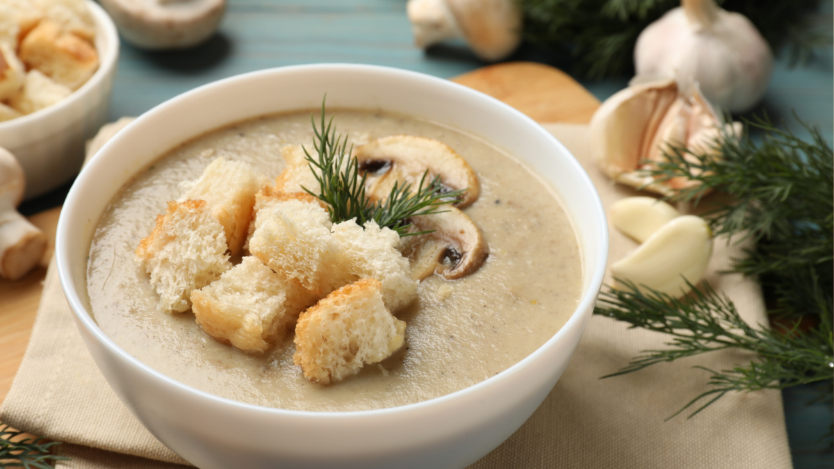 Delicious mushroom cream soup with croutons and dill on table,