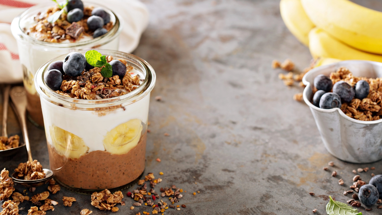 A deliciously layered delight featuring creamy yogurt, fresh bananas, and crunchy granola, garnished with blueberries and mint, perfect for a nutritious dessert or snack.