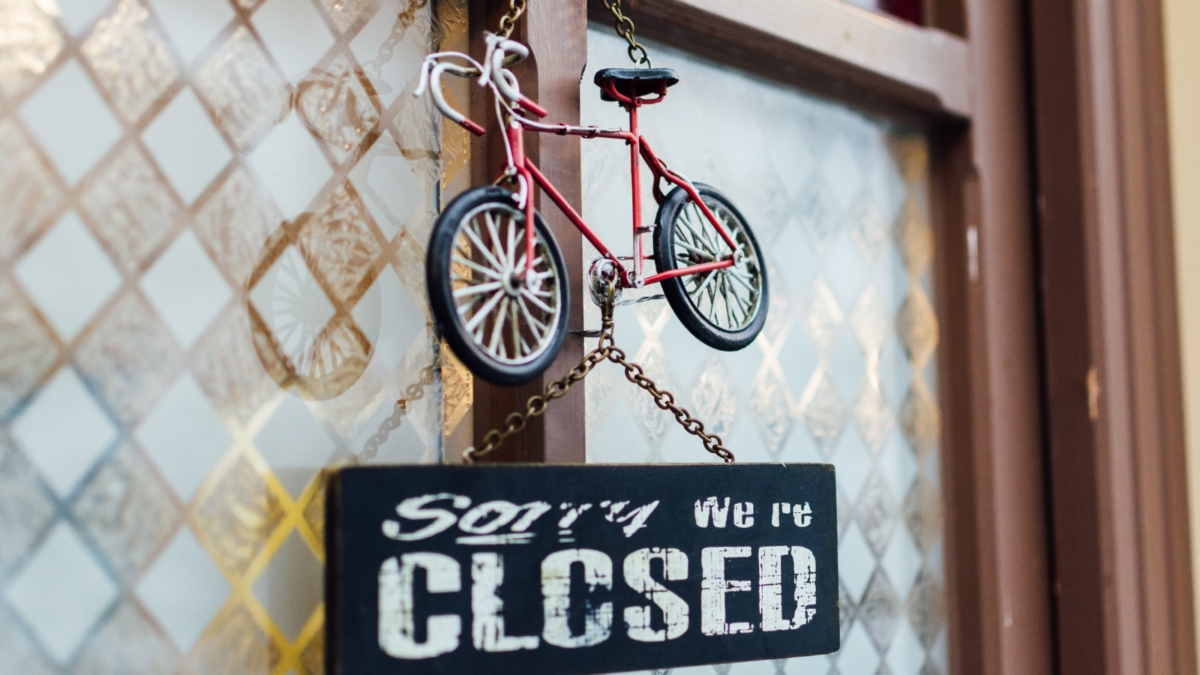 door chalk signboard saying Sorry we are closed with toy bicycle above