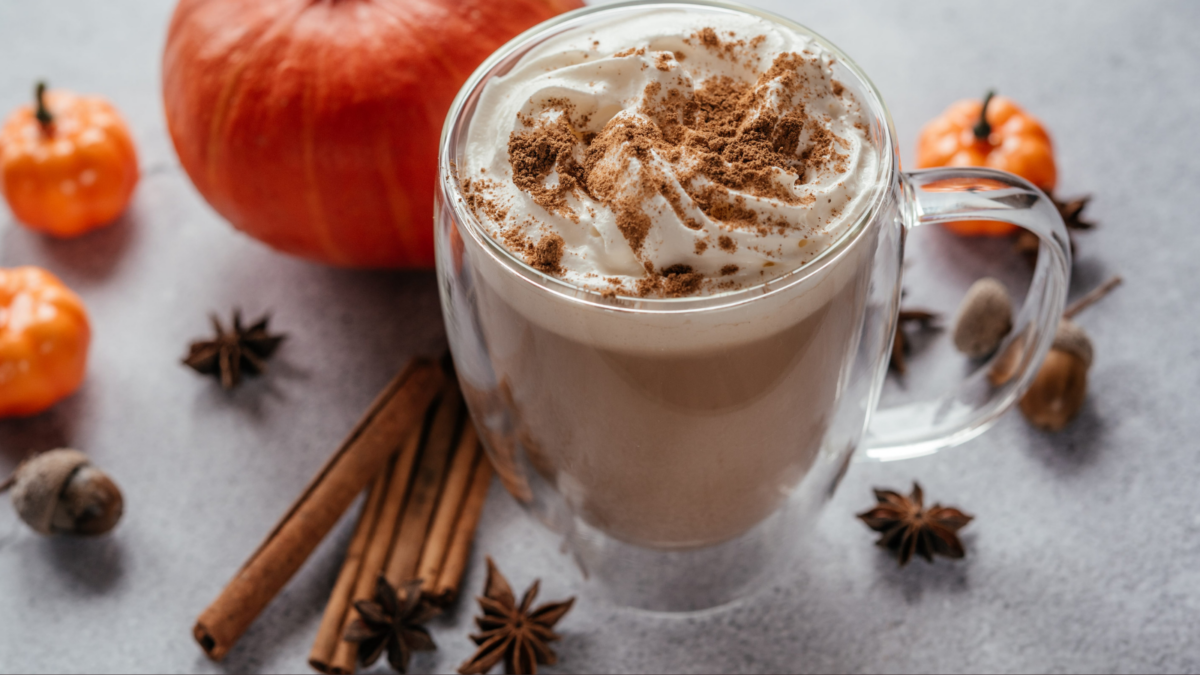 A cozy autumn scene featuring a rich pumpkin spice latte topped with whipped cream and a sprinkle of nutmeg, surrounded by seasonal elements like mini pumpkins and cinnamon sticks, inviting warmth on a crisp day.
