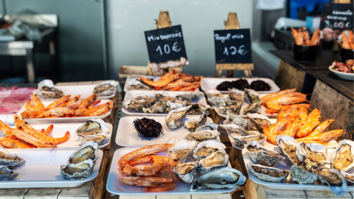 Fresh oysters, shrimp and purple sea urchin in a gourmet fish Market. Image Credit: jordi2r/ 123RF